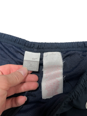 Sötétkék Nike streetwear rövidnadrág címkéi, kézben tartva, hálós béléssel