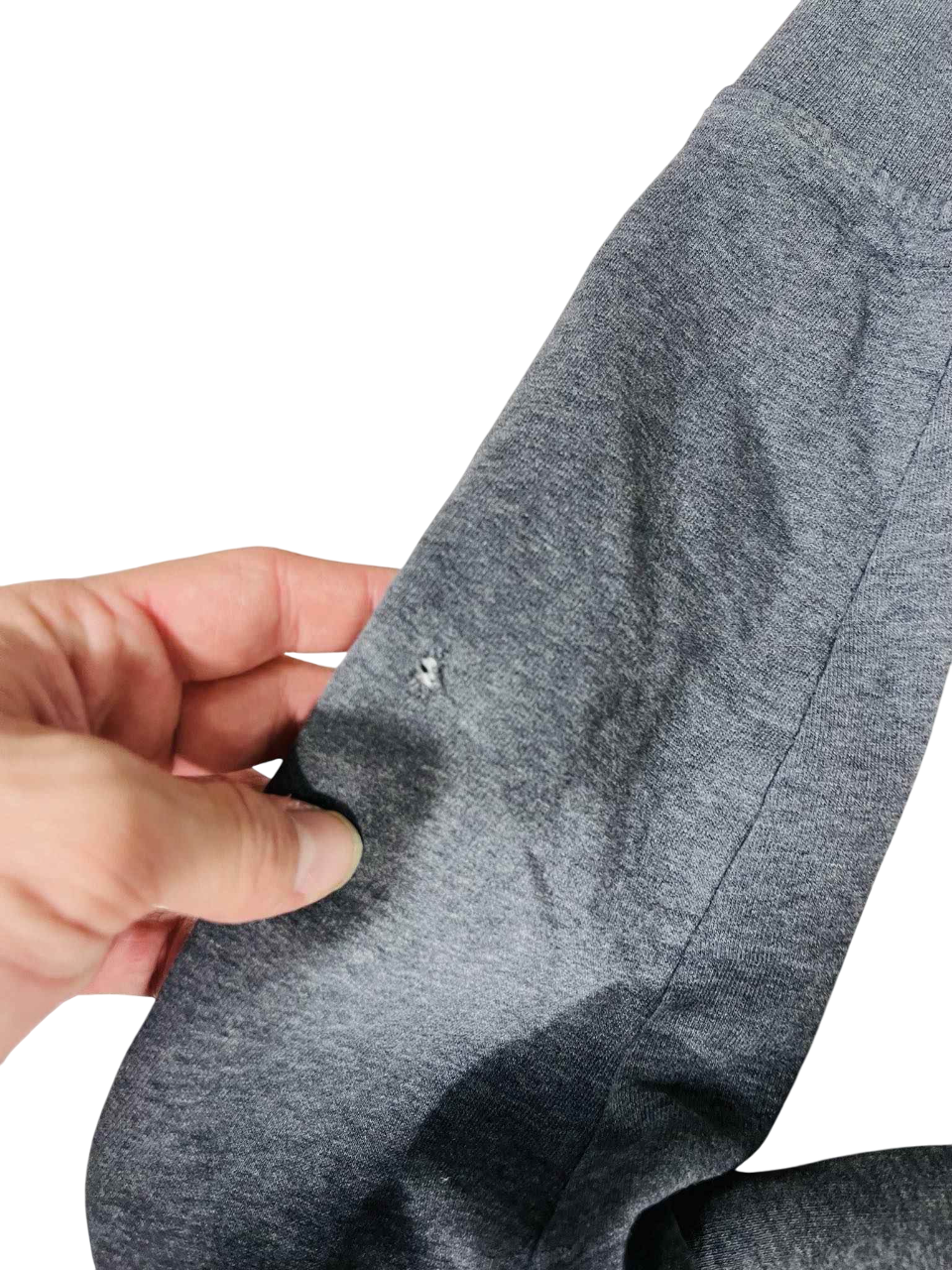 Szürke streetwear pulóver ujján kis lyuk, kéz tartja, vintage divat részlet