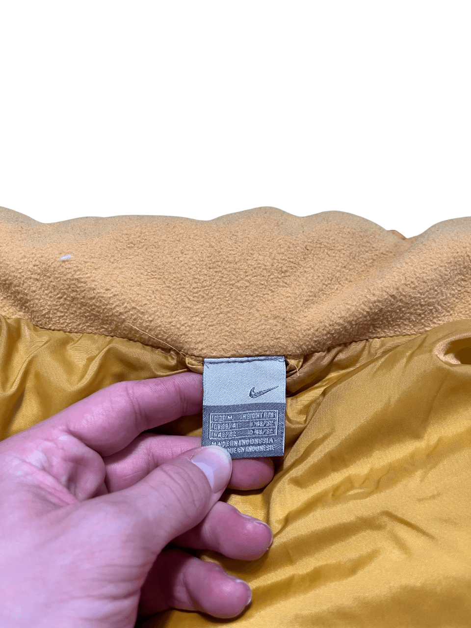 Nike címkés vintage sárga kabát belső címke, streetwear stílus, kezek tartják