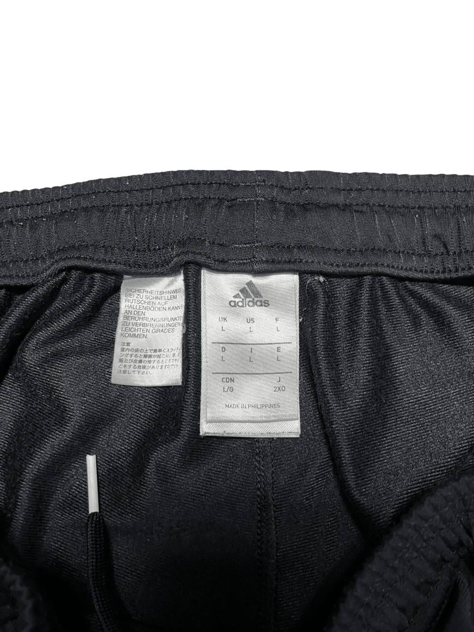 Adidas fekete streetwear nadrág címke közelről, méret és anyag információval