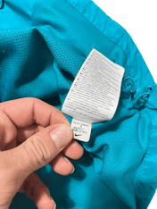 Türkiz Nike streetwear rövidnadrág belső címkéje, részletes anyag- és méretinformációval